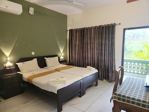 Una habitación de hotel con cama, mesitas de noche, una silla y un balcón con cortinas.