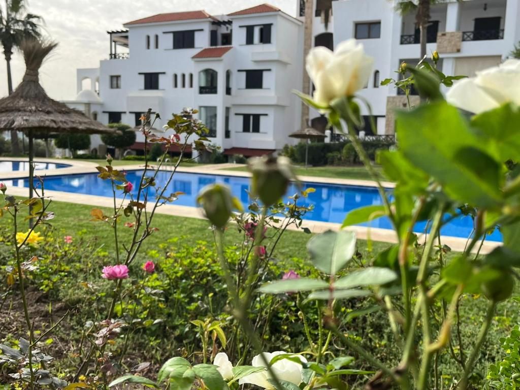 A pool surrounded by greenery and buildings in the background.