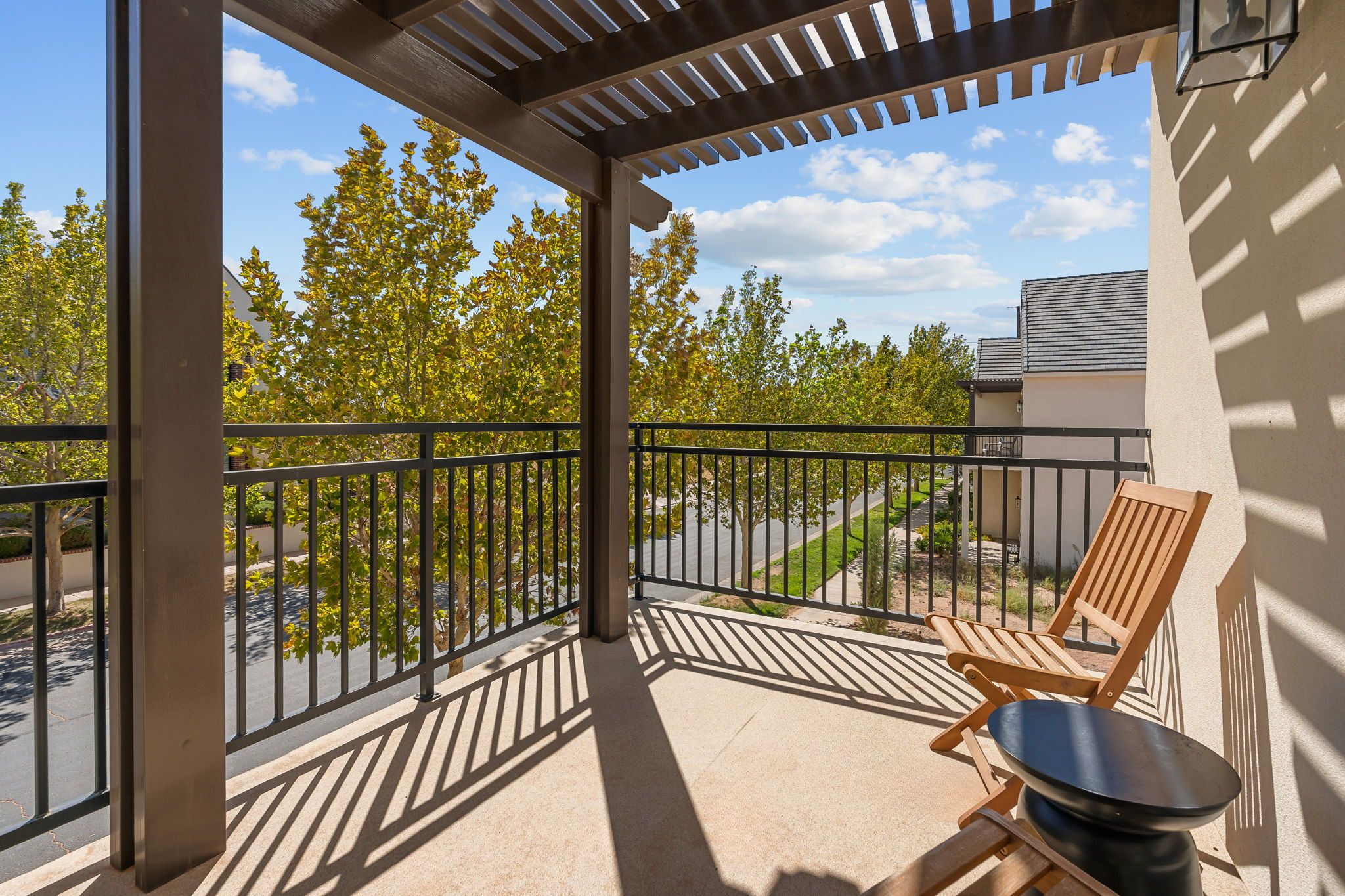A covered balcony with a metal railing, a wooden chair, and a table.