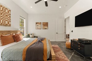Ein Schlafzimmer mit einem Bett, einem Schminktisch, einem Fernseher und Bildern an der Wand.