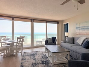 A spacious living area with a view of the ocean, a balcony, and a modern interior design. - Peck7NE Oceanfront Condo - Magical Views, Heated Pool, Hot Tub, Beach Decor (Daytona Beach)