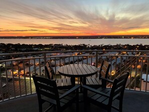 Un balcón con mesa y sillas que ofrece vistas a un paisaje urbano al atardecer.
