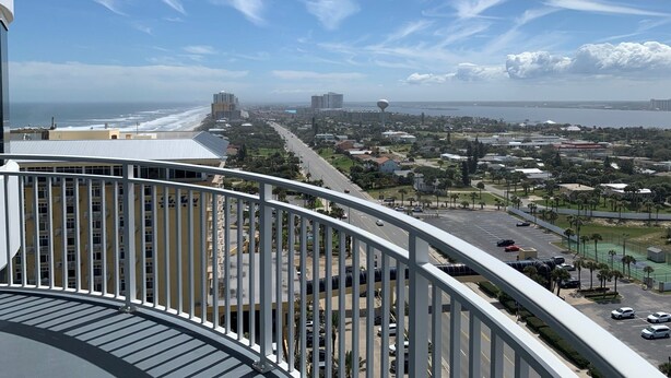 Ein Balkon mit Blick auf eine Küstenstadtlandschaft, inklusive Strand und Gebäuden.