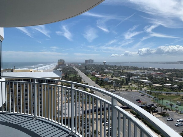 Un balcón con vistas a una ciudad costera, incluyendo una playa y edificios.