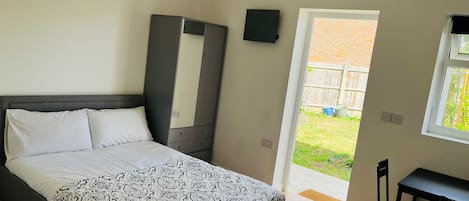 A bedroom with a bed, a wardrobe, a desk, and a window.