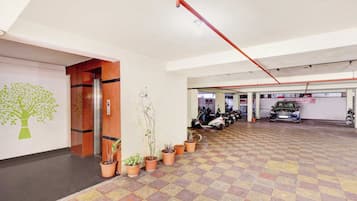 Un parking avec un sol à carreaux, des plantes en pot et un espace réservé au stationnement des scooters.