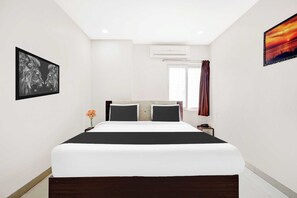 Un dormitorio moderno con una cama grande, una mesita de noche, un florero y un cuadro en la pared.