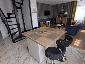 A modern kitchen with a central island, bar stools, a sofa, and a dining table. - Duplex with Spa & Sauna - 4 guests (LA SENTINELLE)
