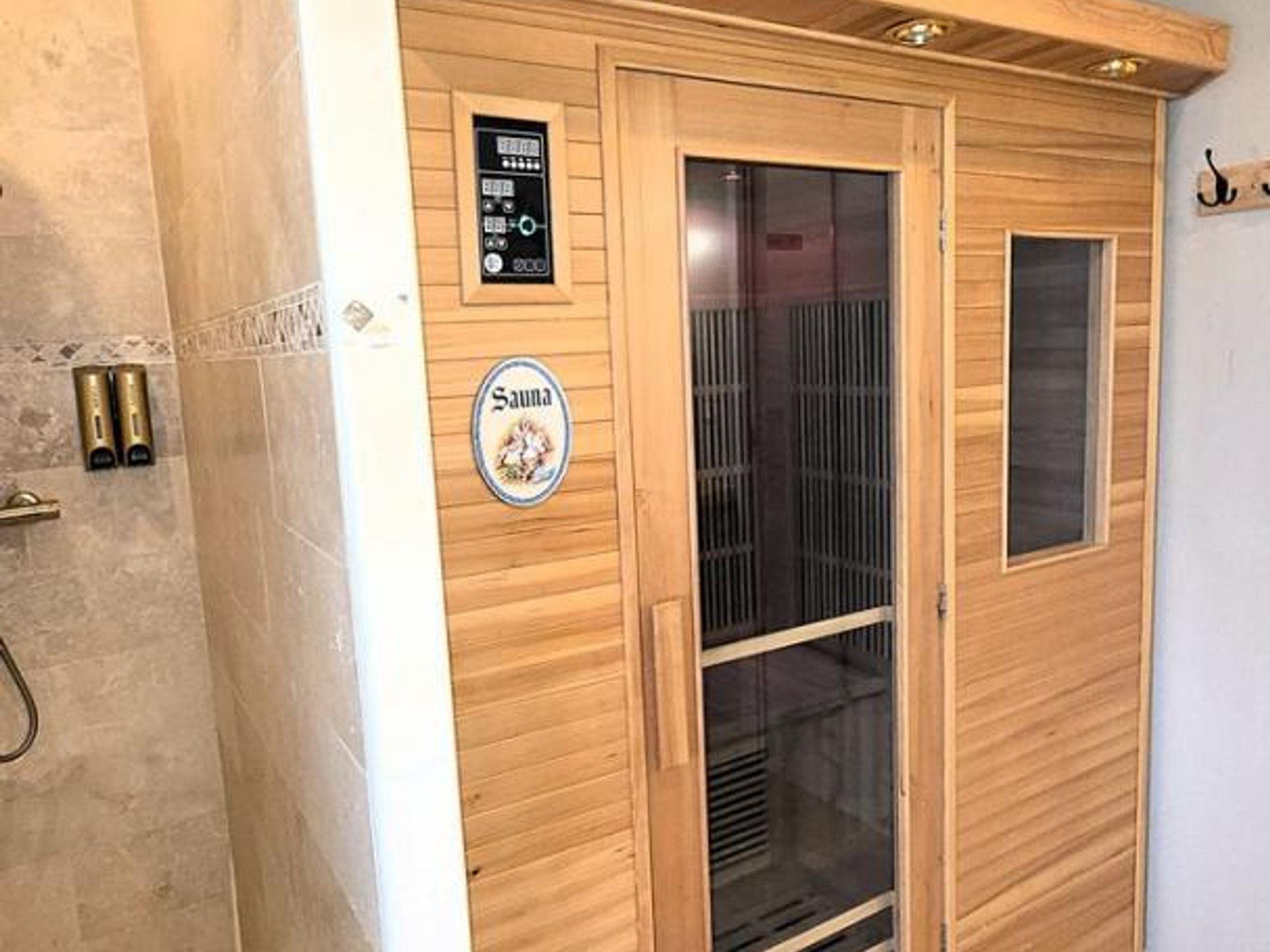 Un sauna avec des murs en bois, une porte en verre et un panneau de commande.