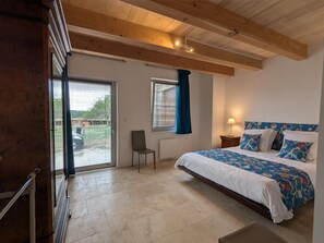 A bedroom with a bed, a chair, a window with curtains, and a view of the outside. - Welcoming house, pets OK - 8 guests (Nanteuil-en-Vallée)