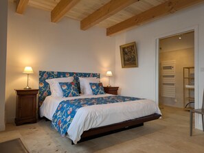 A bedroom with a bed, two bedside lamps, a wooden headboard, a painting on the wall, and a bathroom visible through an open door. - Welcoming house, pets OK - 8 guests (Nanteuil-en-Vallée)