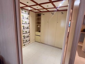 A room with a tiled floor, a wardrobe with multiple doors, a shelf with potted plants, and a lamp. - Convenient apartment near slopes - 6 guests (Les Angles)