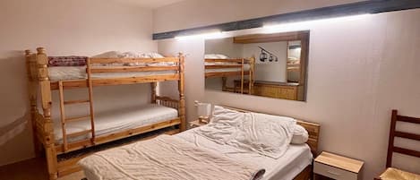 A bunk bed room with a mirror and a small table.