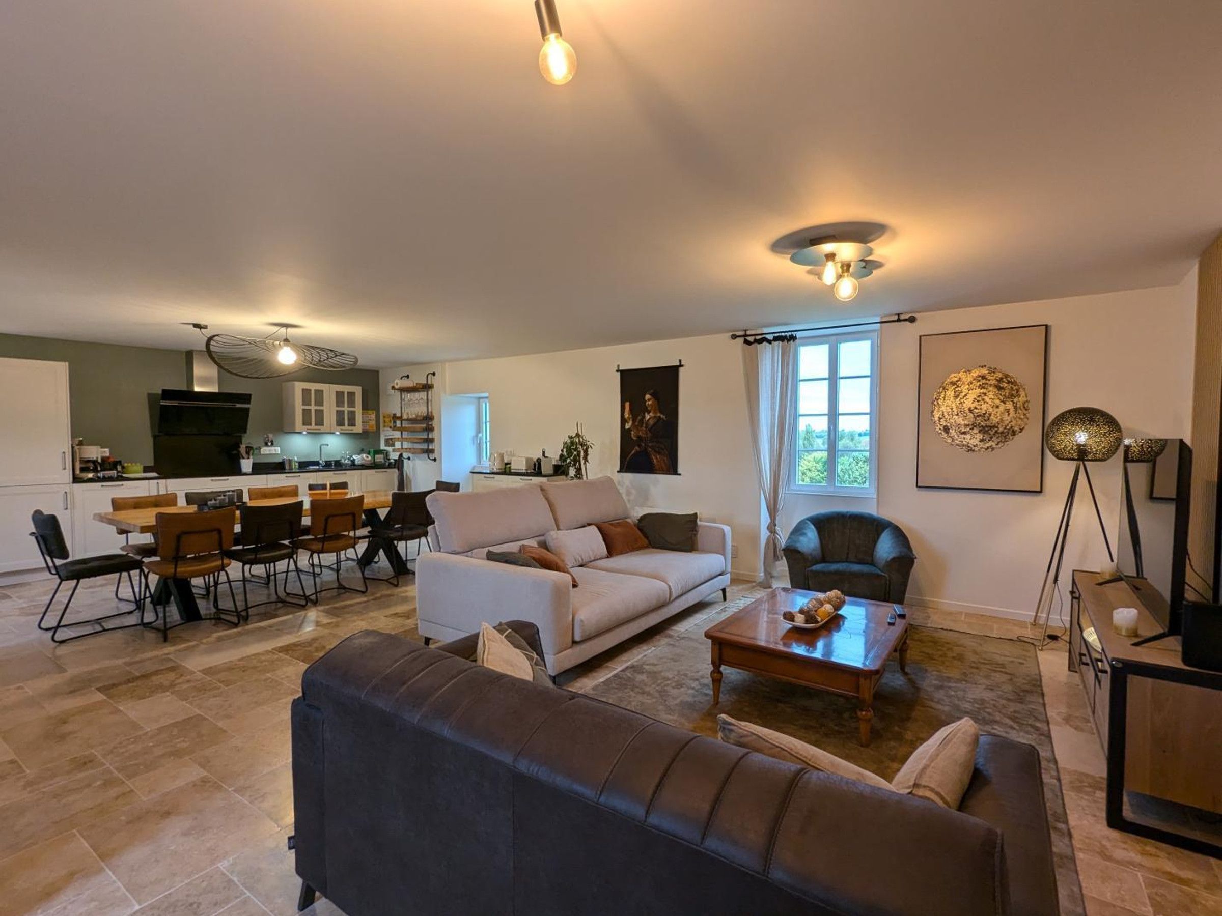 A spacious living area with a sofa, coffee table, and dining set.