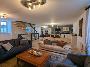 Een moderne woonkamer met een trap, een eethoek en een keuken.