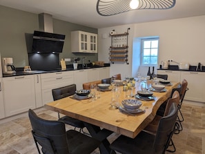 Cozinha moderna com área de jantar, equipada com cafeteira, copos de vinho e diversos utensílios de cozinha.