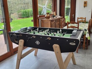 A foosball table in a room with a view of a windmill and greenery outside. - Spacious house, preserved nature - Total serenity (CASSEL)