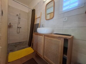 Ein Badezimmer mit Dusche, Waschbecken, Spiegel und einer gelben Matte.
