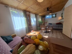 Ein Zimmer mit Esstisch, Stühlen, einer Couch, einem Bett und einem Deckenventilator.