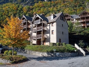 Ein mehrstöckiges Hotel mit Balkonen, einem Parkplatz und einer Bergkulisse.