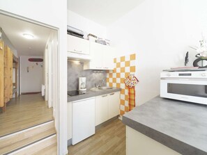 A compact kitchen with a microwave, coffee maker, and a checkered wall. - Studio with mountain view - 6 guests (Gourette)