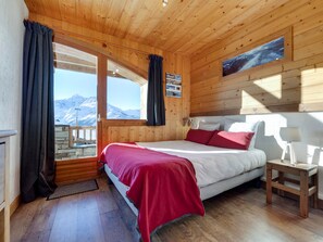 Ein Schlafzimmer einer Holzhütte mit einem Bett, einem Nachttisch und Bergblick.
