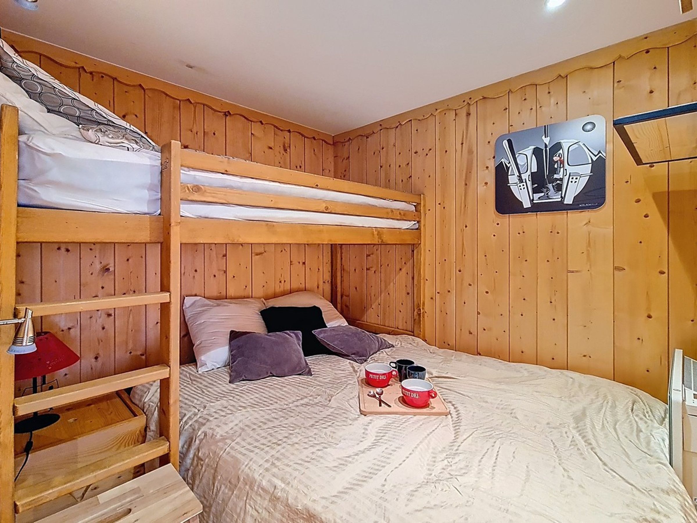 Una camera con un letto a castello, una testiera in legno, un tavolino con delle tazze e un'opera d'arte appesa al muro.