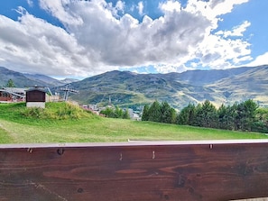 A mountainous landscape with a small building and a wooden fence. - Cozy ski-in/ski-out apartment, south-facing balcony (Les Menuires)