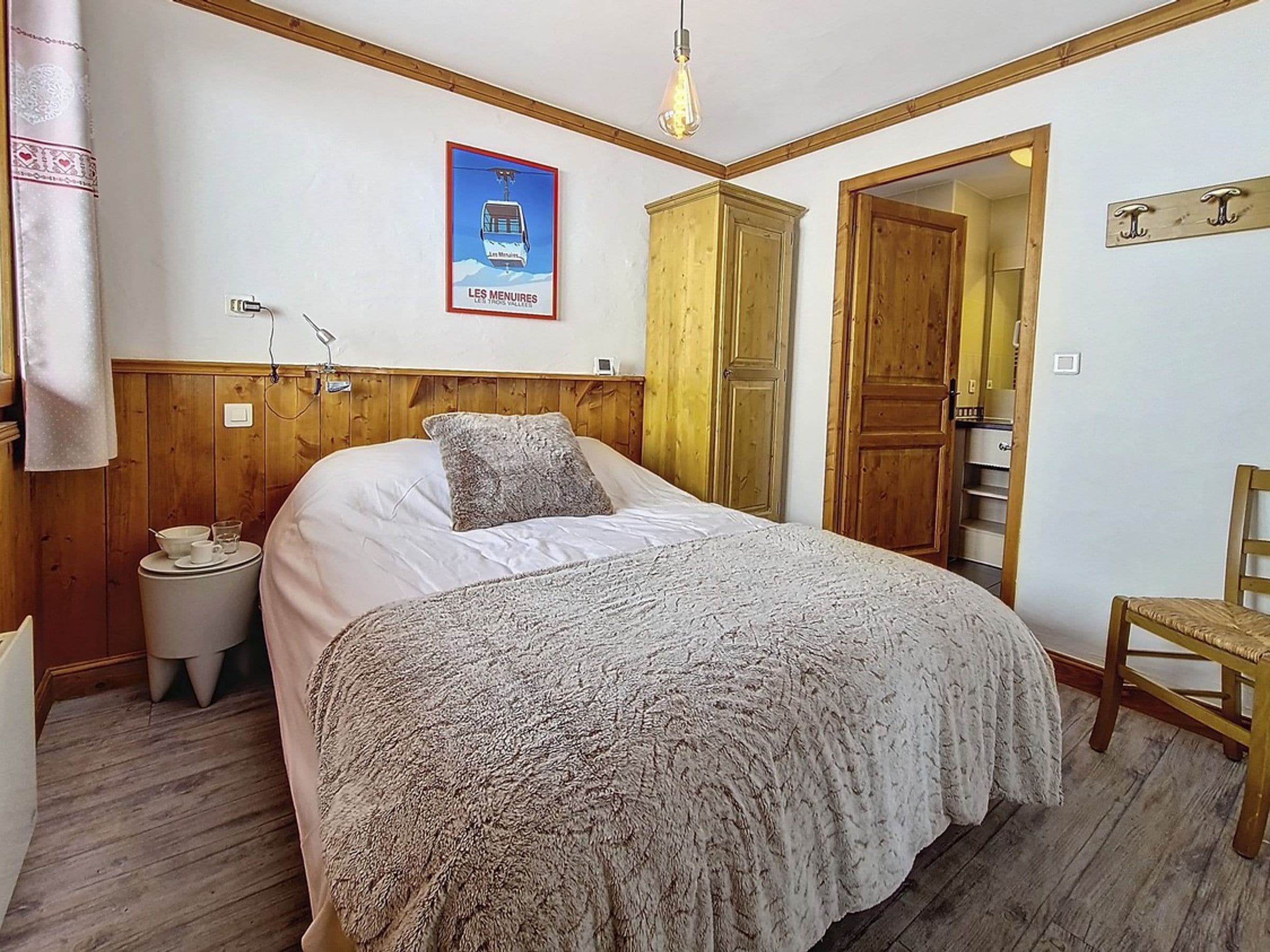 Ein Schlafzimmer mit Bett, Nachttisch, Lampe und einem Poster an der Wand.