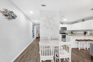 Uma cozinha moderna com armários brancos, uma ilha central e um detalhe decorativo em formato de roda de navio.