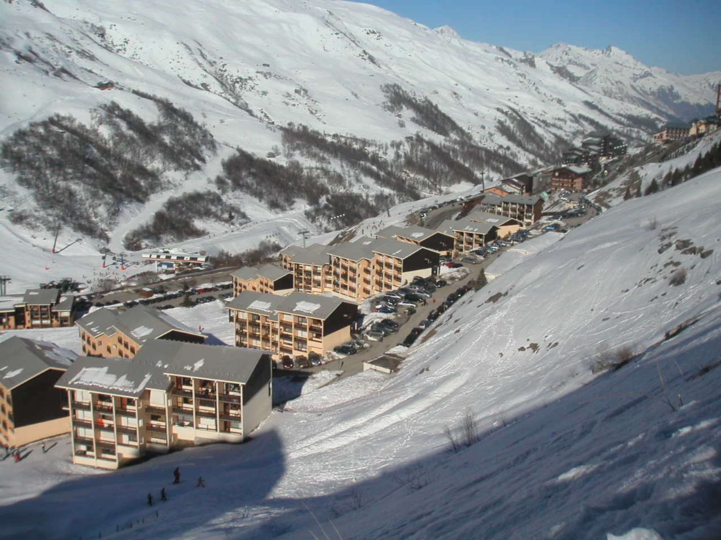 A snow-covered mountain town with multiple multi-story buildings, likely hotels, arranged along a hillside.