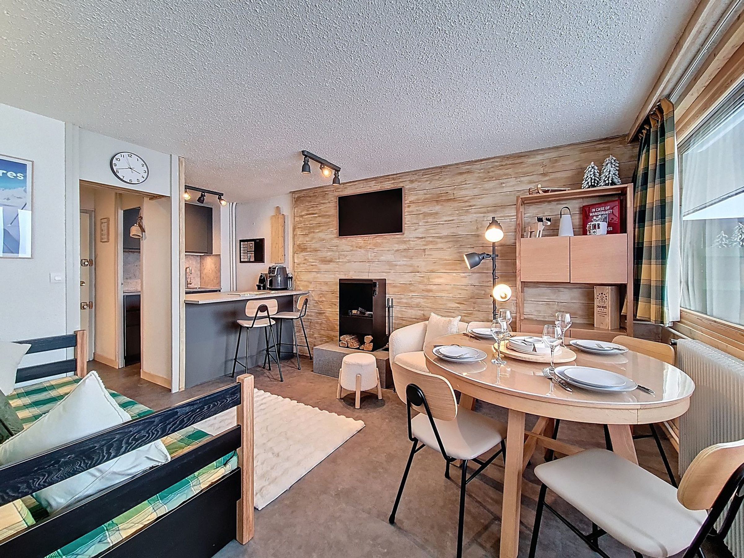 Uma sala de estar acolhedora com lareira, um espaço de jantar com mesa redonda e uma cozinha.