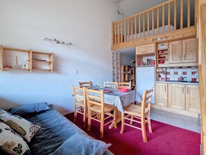 Um espaço compacto com mesa de jantar, cadeiras, beliche e kitchenette.