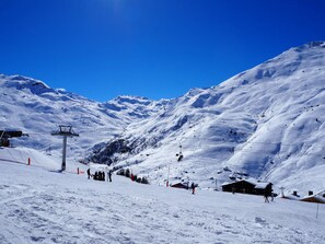 A snow-covered mountain with a ski lift, a wooden lodge, and a clear blue sky. - Bright apartment with southeast balcony, slopeside (Les Menuires)