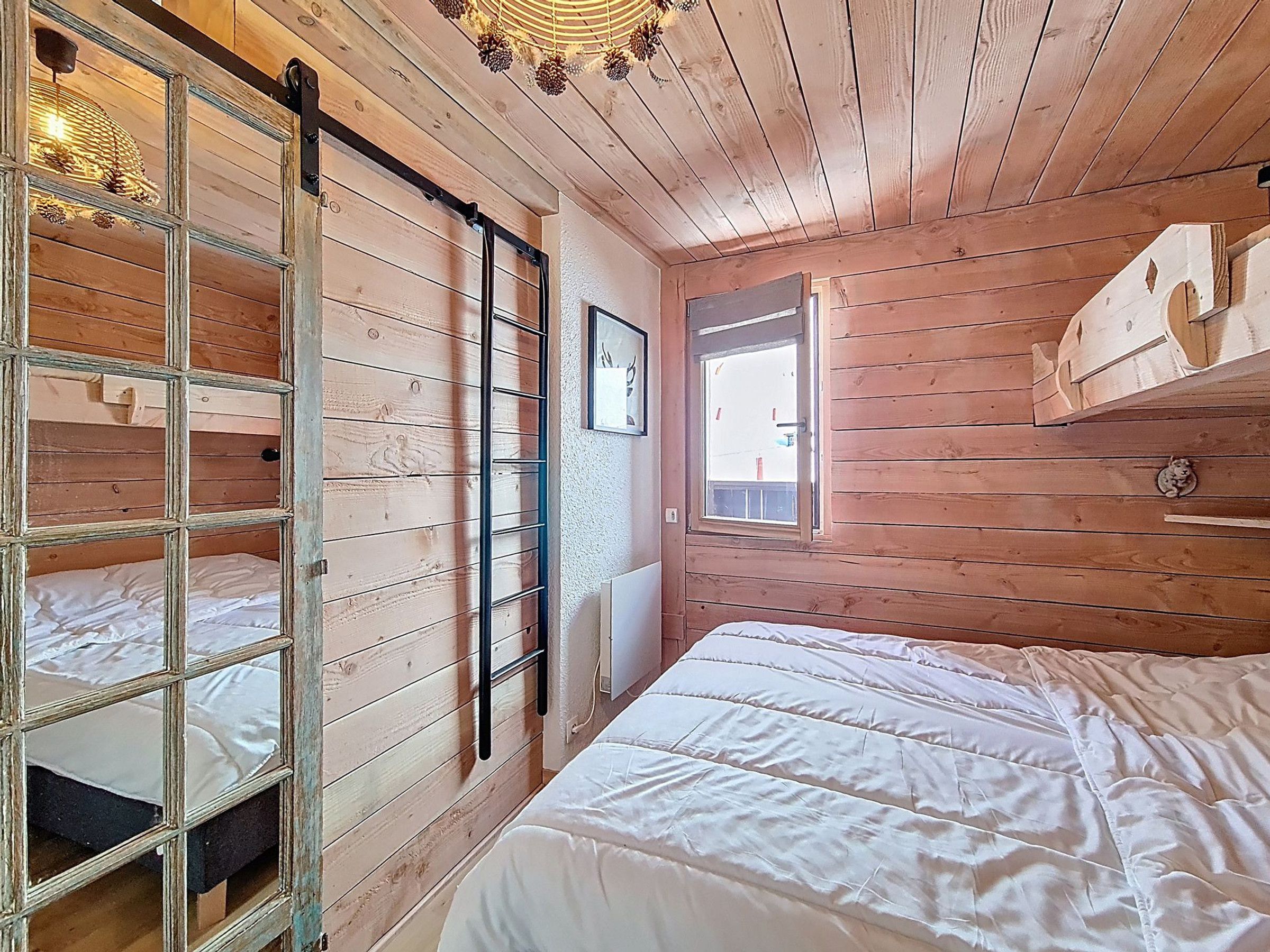 A wooden room with bunk beds, a window, and a shelf.