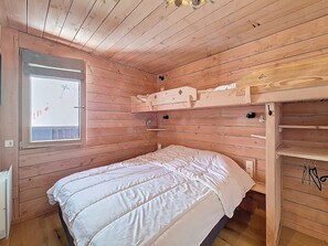 Ein Zimmer mit Holzboden, einem Etagenbett, einem Fenster und einer eingebauten Ablagefläche.