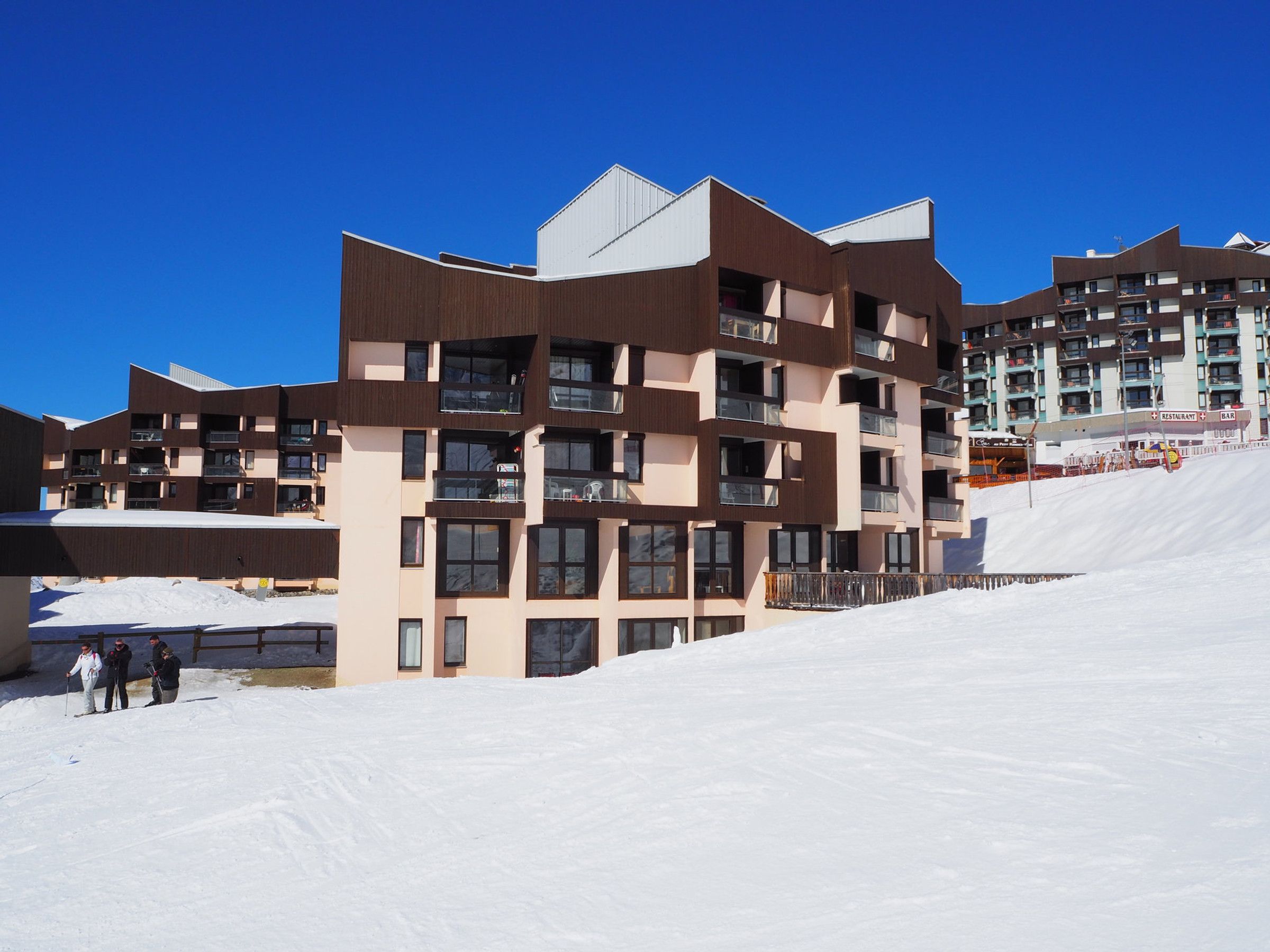 A modern multi-story building with balconies and large windows, situated in a snowy environment.