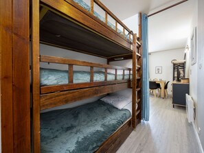 Ein Stockbett mit Schreibtisch und Stuhl in einem Zimmer mit hellem Holzboden.