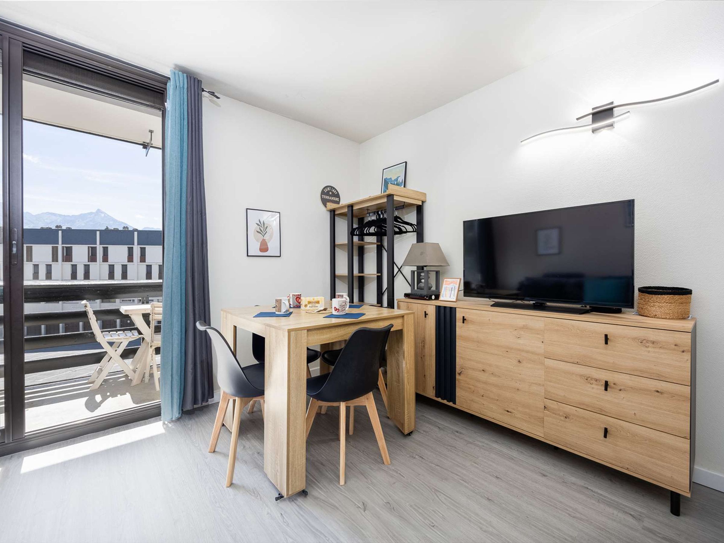 Una habitación moderna con una mesa de comedor, sillas, un televisor y un armario.