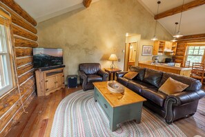 A log cabin interior with a living room, a kitchen, and a dining area. - NEW Stirrup Summit Cabin | Ski-In/Out 2BR Hot Tub (Big Sky)