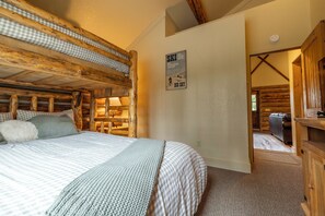 A cozy room with a bunk bed, a poster on the wall, and a view of the outside. - NEW Stirrup Summit Cabin | Ski-In/Out 2BR Hot Tub (Big Sky)
