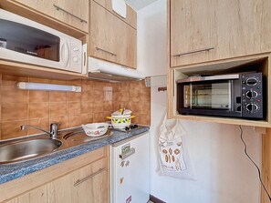 A compact kitchen with a microwave, stove, and sink. - 2-room apartment at the slopes with balcony (Les Menuires)