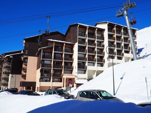 A multi-story hotel with balconies and a ski lift in the background. - Renovated apartment, near slopes - 6 guests (Les Menuires)