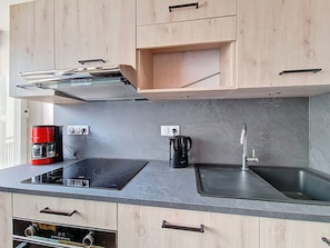 A modern kitchen with a built-in oven, a coffee maker, a kettle, and a sink. - Renovated apartment, near slopes - 6 guests (Les Menuires)