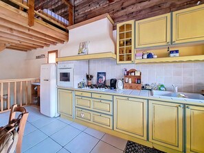 Eine Küche mit gelben Schränken, einem weißen Kühlschrank und einer gefliesten Spritzschutzwand.