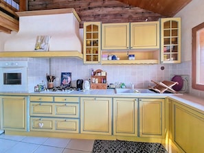 A kitchen with yellow cabinets, a stove, and a tiled backsplash. - Charming village house. Terrace. 5 min from St Martin de Belleville (Saint-Martin-de-Belleville)