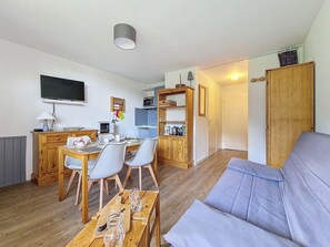 A compact living space with a kitchenette, dining area, and a sofa. - Cozy studio with balcony, ski-in ski-out (Les Menuires)