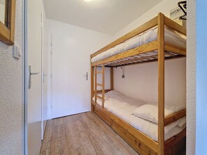 A bunk bed room with a wooden frame, a door, and a light switch on the wall. - Cozy studio with balcony, ski-in ski-out (Les Menuires)