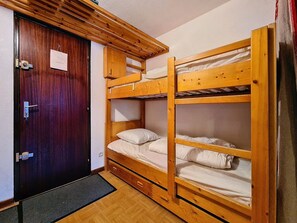 Ein Schlafraum mit Etagenbetten, einer Holztür und einem kleinen Schreibtisch.