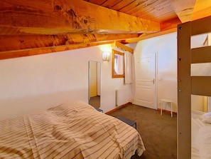 A bedroom with a bed, a mirror, a door, and a radiator. - 3-room apartment, southwest balcony, at the foot of slopes (Les Menuires)